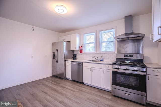 kitchen with stainless steel appliances, wall chimney range hood, a sink, and light countertops