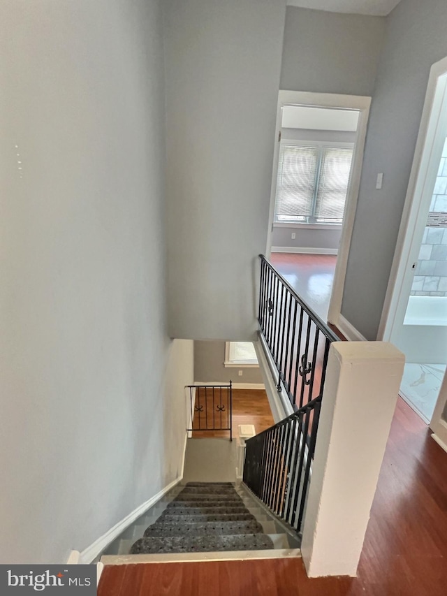 stairway featuring healthy amount of natural light, wood finished floors, and baseboards