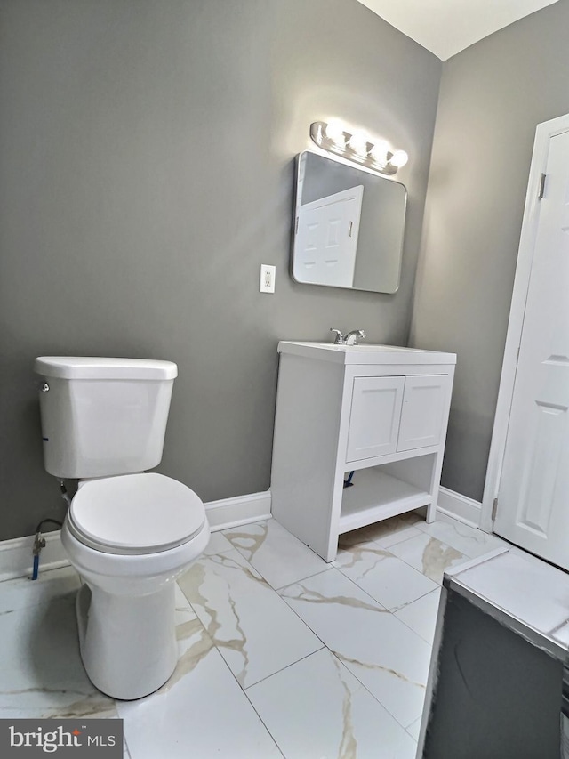 bathroom with marble look tile flooring, baseboards, toilet, and vanity