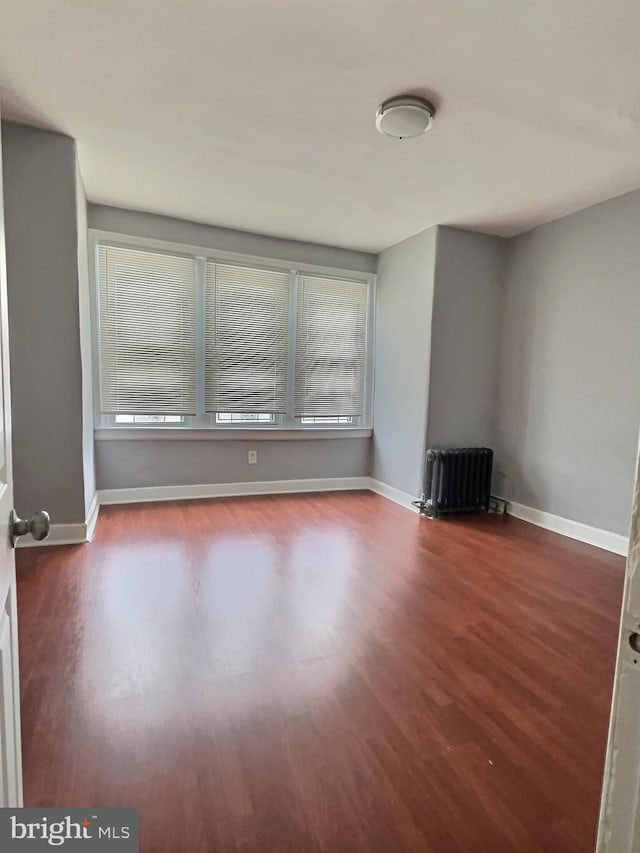 unfurnished room with radiator, wood finished floors, and healthy amount of natural light
