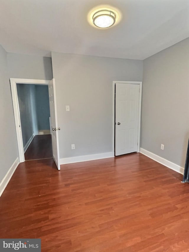 unfurnished bedroom with wood finished floors and baseboards