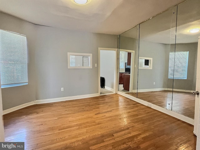 unfurnished bedroom with hardwood / wood-style floors, a closet, and baseboards