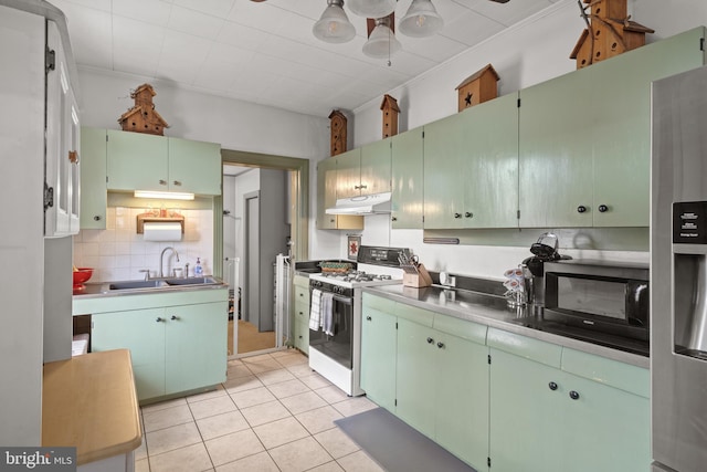 848 Houston St, Columbia, PA 17512 - kitchen featuring white range with gas stovetop, a sink, under cabinet range hood, stainless steel fridge, and light tile patterned flooring