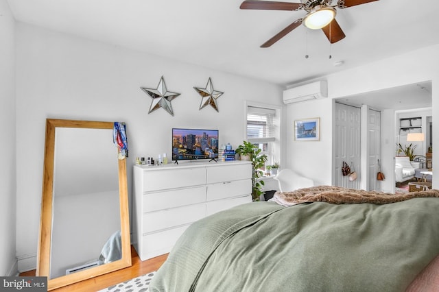 bedroom with a wall mounted air conditioner, wood finished floors, and ceiling fan