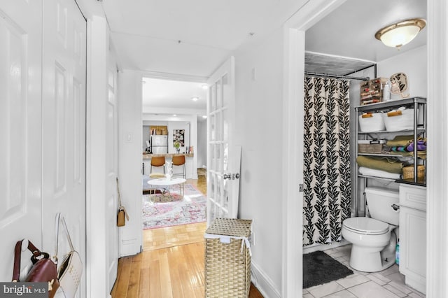 full bathroom featuring toilet, a shower with shower curtain, and wood finished floors