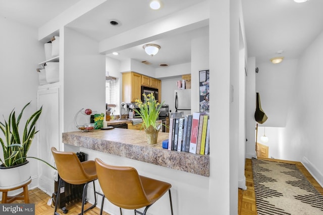kitchen featuring black microwave, baseboards, a sink, light countertops, and recessed lighting