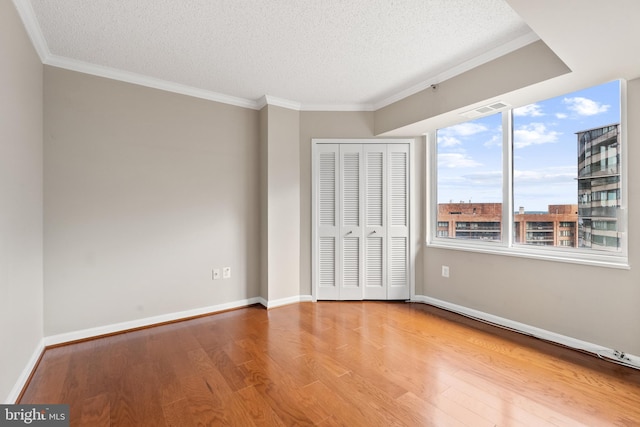 1300 Crystal Dr Unit 1408S, Arlington, VA 22202 - unfurnished bedroom featuring a textured ceiling, wood finished floors, a closet, crown molding, and baseboards