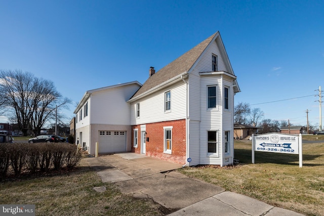 225 S Hanover St, Pottstown, PA 19465 - view of side of property featuring a garage, a chimney, concrete driveway, a lawn, and brick siding