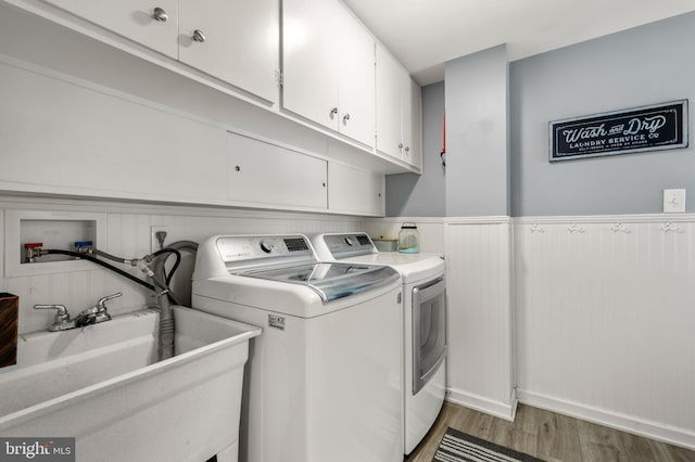 washroom featuring cabinet space, washer and dryer, light wood-style floors, and a wainscoted wall
