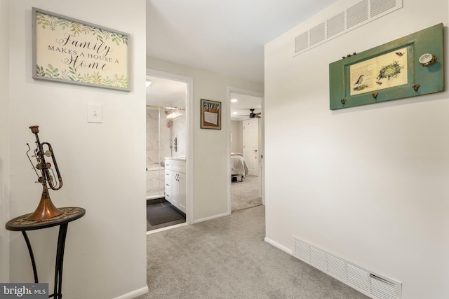hallway featuring carpet flooring and baseboards