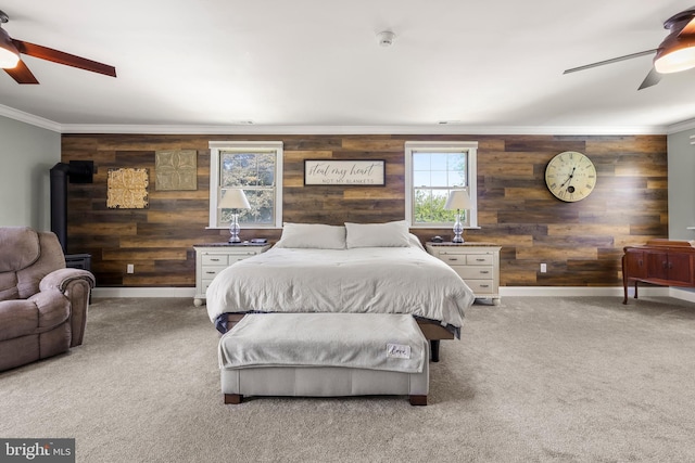 bedroom with wooden walls, crown molding, carpet, baseboards, and a ceiling fan