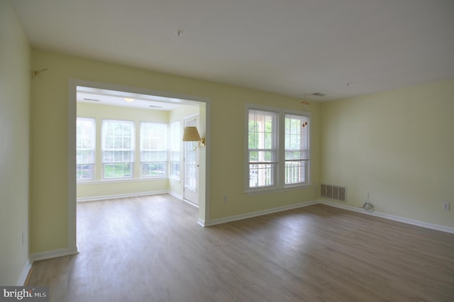 spare room with wood finished floors, plenty of natural light, and baseboards