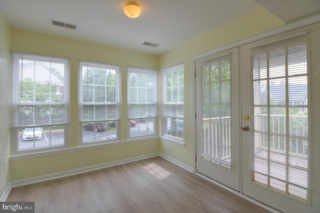 unfurnished sunroom featuring french doors, baseboards, and wood finished floors