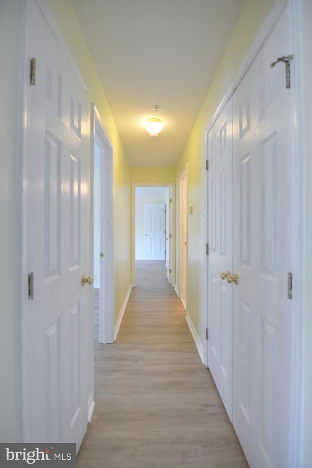 corridor featuring baseboards and light wood-style floors