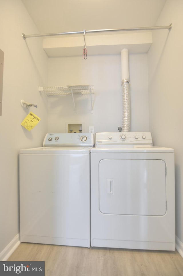 laundry area featuring independent washer and dryer, baseboards, and light wood-style flooring
