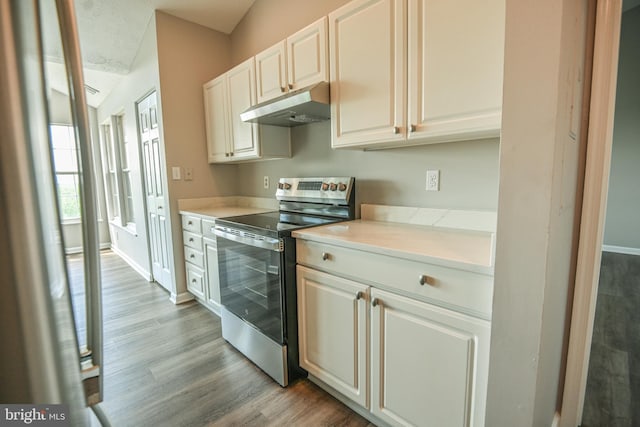 kitchen with electric stove, under cabinet range hood, light wood-style floors, light countertops, and baseboards
