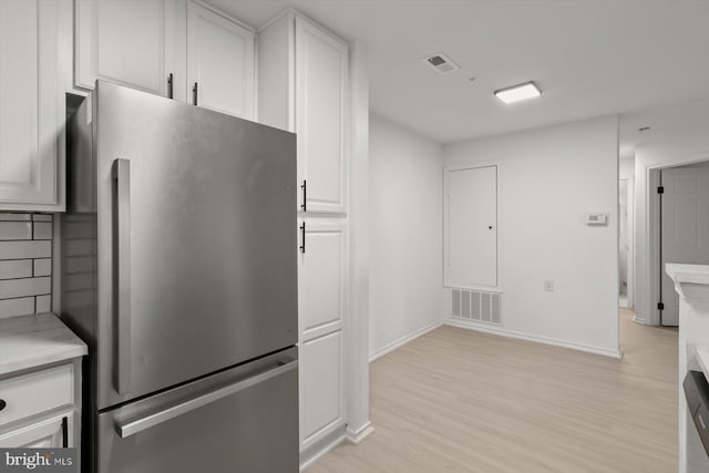 kitchen featuring freestanding refrigerator, light countertops, white cabinets, light wood-type flooring, and baseboards
