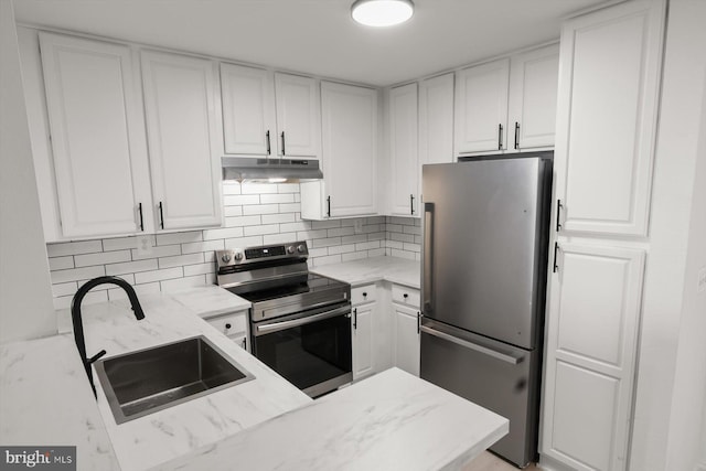 kitchen featuring stainless steel appliances, under cabinet range hood, a sink, and white cabinets
