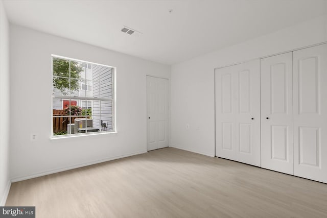 unfurnished bedroom with wood finished floors, baseboards, and a closet