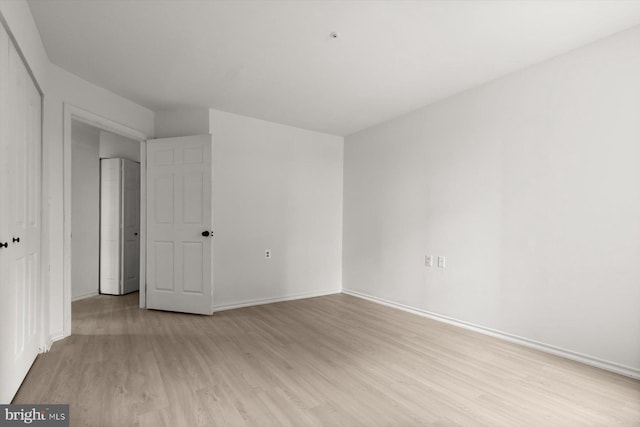 unfurnished bedroom with light wood-style flooring, baseboards, and a closet