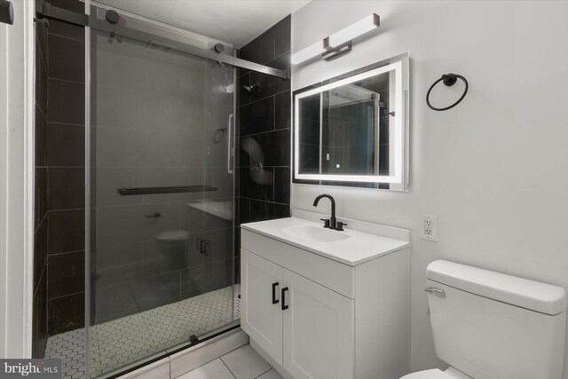 full bath featuring toilet, a shower stall, vanity, and tile patterned floors