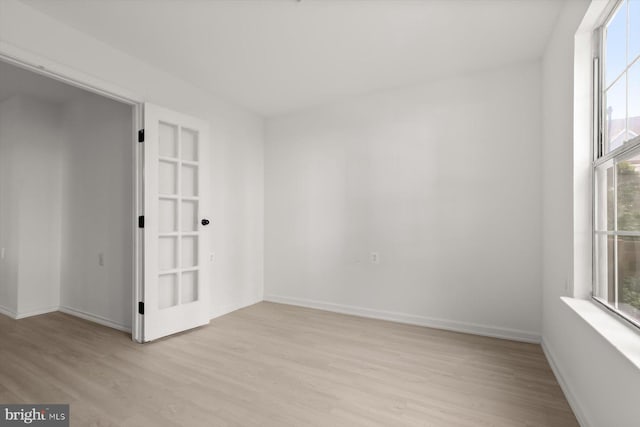 spare room featuring light wood-style flooring, plenty of natural light, and baseboards