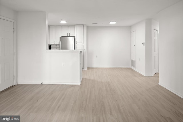 unfurnished living room featuring light wood finished floors and baseboards