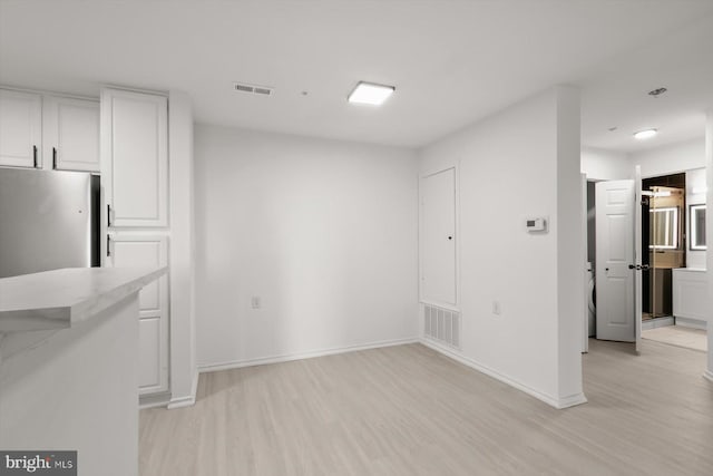 unfurnished dining area with light wood-style flooring and baseboards