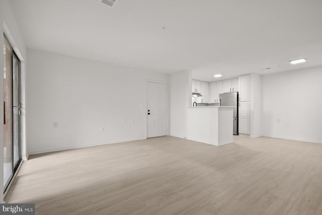 unfurnished living room with light wood-style flooring and baseboards