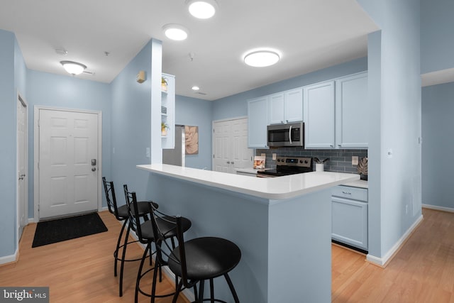 12708 Found Stone Rd Unit 3-304, Germantown, MD 20876 - kitchen featuring stainless steel appliances, a breakfast bar, light wood-style flooring, backsplash, and light countertops