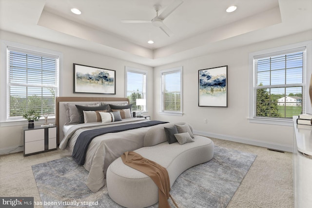 bedroom featuring a raised ceiling, light colored carpet, multiple windows, and recessed lighting