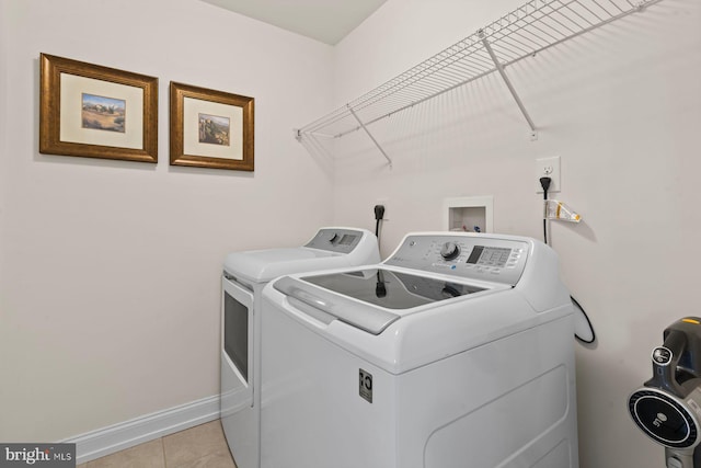 washroom with separate washer and dryer, light tile patterned flooring, and baseboards