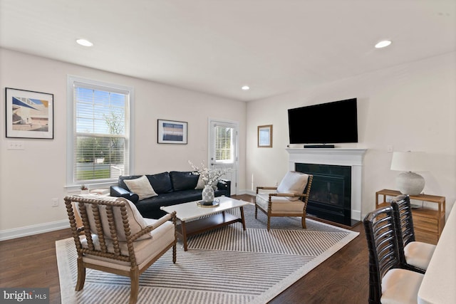 living area featuring baseboards, dark wood-style floors, recessed lighting, and a fireplace with flush hearth