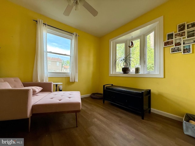 living area with wood finished floors, a ceiling fan, and baseboards