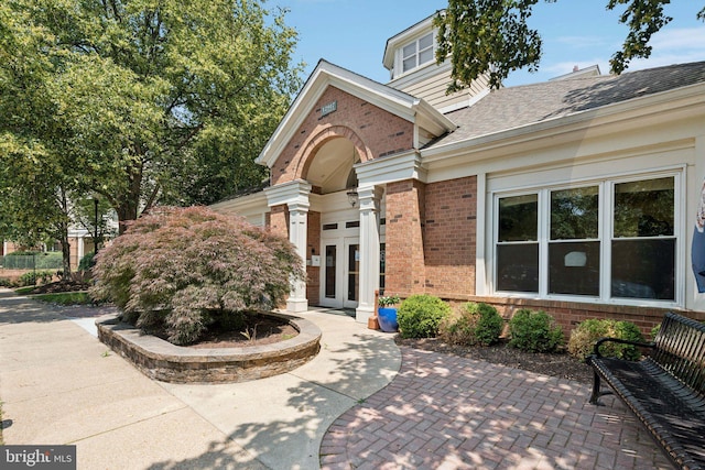 2204 Westcourt Ln Unit 122, Herndon, VA 20170 - view of exterior entry featuring brick siding, roof with shingles, a patio area, and french doors