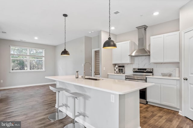 kitchen with electric range, wall chimney range hood, a sink, dark wood-type flooring, and a kitchen island with sink