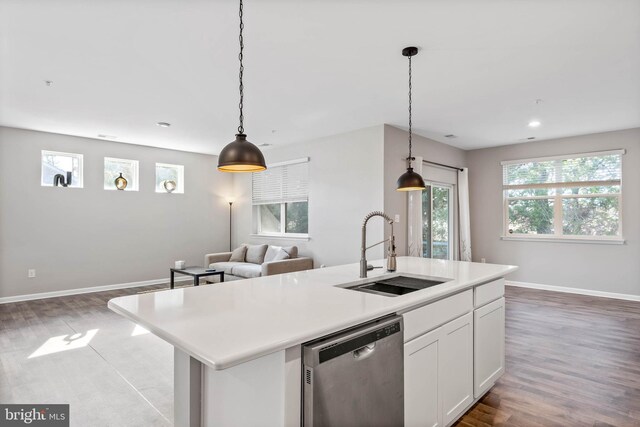 kitchen featuring stainless steel dishwasher, a sink, light wood finished floors, open floor plan, and white cabinets