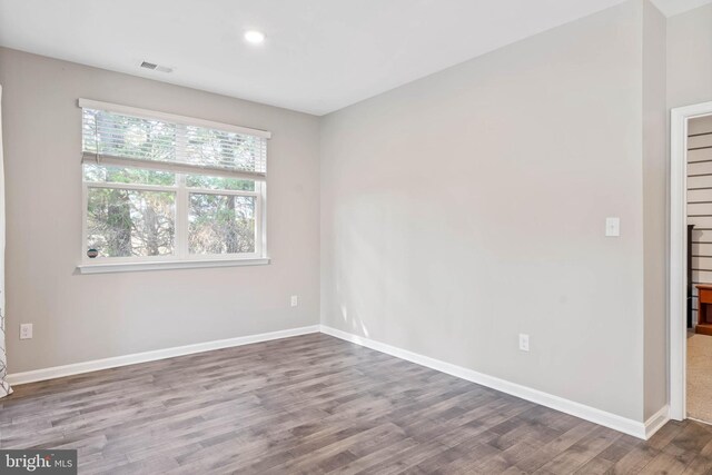 spare room with wood finished floors, baseboards, and recessed lighting
