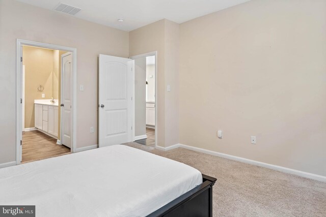 bedroom with baseboards, connected bathroom, and carpet
