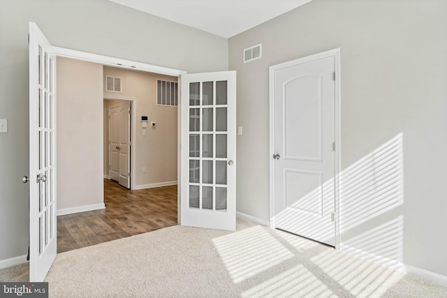 hallway featuring french doors, carpet floors, and baseboards