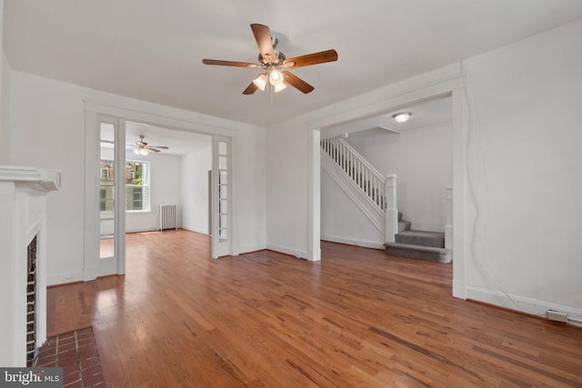 1609 E 33rd St, Baltimore, MD 21218 - unfurnished living room with radiator heating unit, a ceiling fan, wood finished floors, and stairs