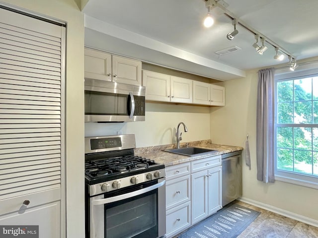 7972 Lakecrest Dr, Greenbelt, MD 20770 - kitchen with stainless steel appliances, a sink, white cabinetry, baseboards, and track lighting