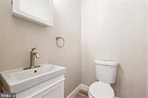 bathroom featuring toilet, baseboards, and vanity