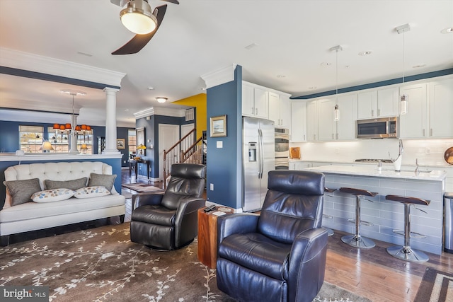 801 Skippers Ln, Annapolis, MD 21401 - living room with crown molding, dark wood-type flooring, decorative columns, ceiling fan, and stairs