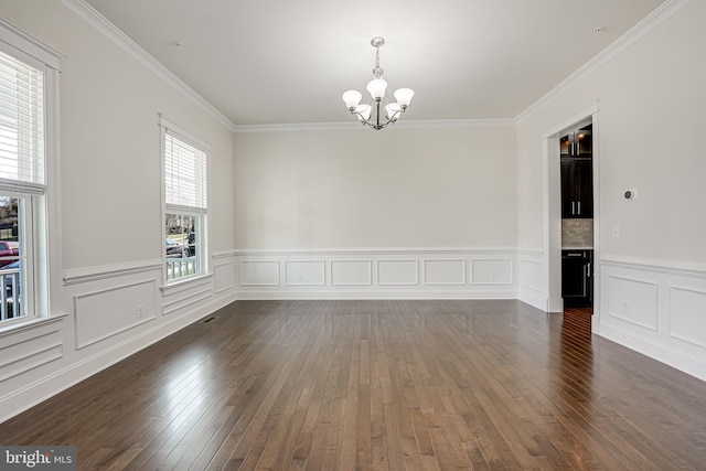 unfurnished room with a chandelier, hardwood / wood-style flooring, ornamental molding, a wainscoted wall, and a decorative wall