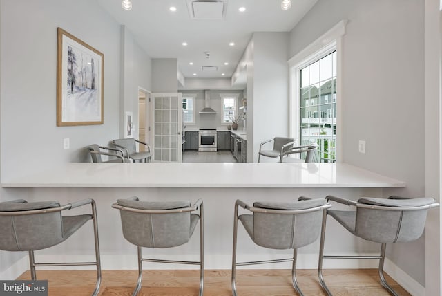 kitchen with electric stove, a peninsula, recessed lighting, wood finished floors, and baseboards