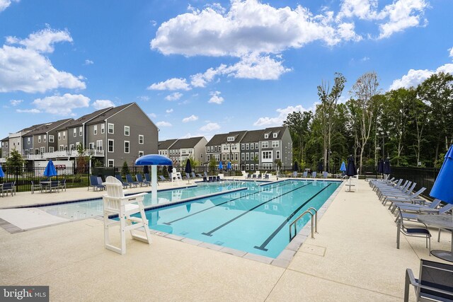 community pool featuring fence, a patio area, and a residential view