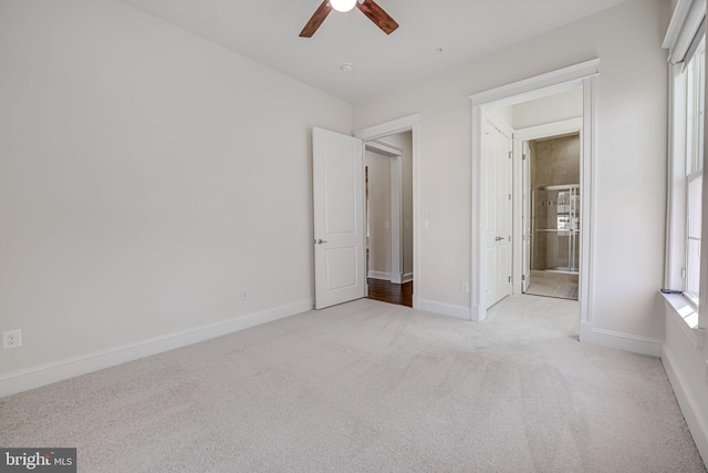 unfurnished bedroom featuring carpet, baseboards, ensuite bath, and ceiling fan