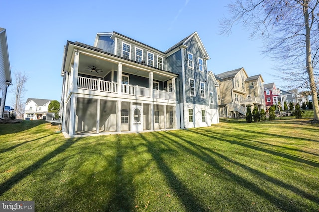 back of house with a ceiling fan, a balcony, a yard, and a residential view