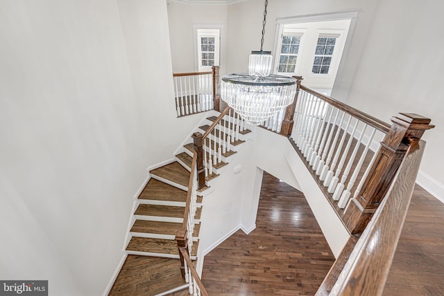 staircase with a chandelier, wood finished floors, and baseboards